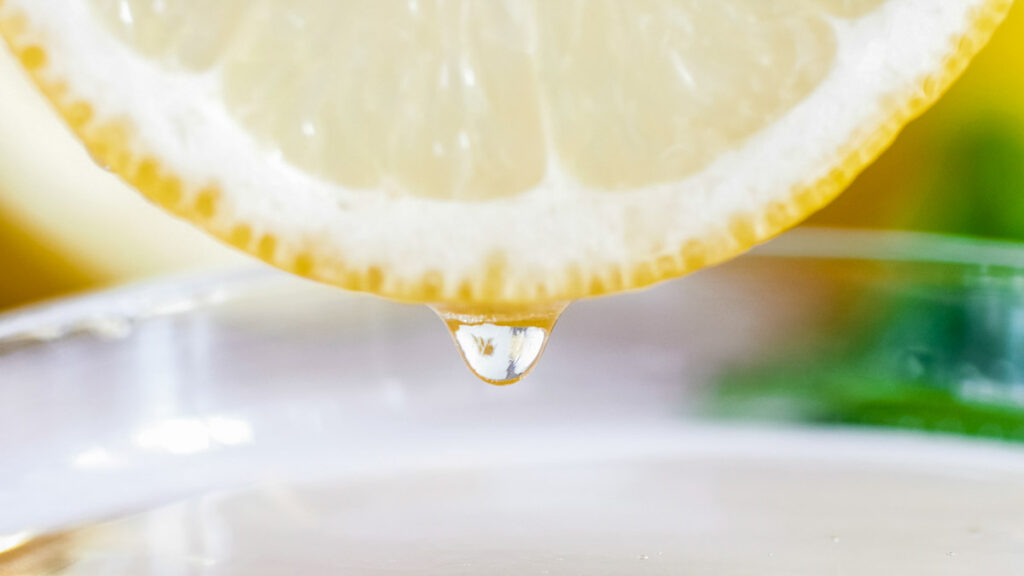 Macro image of juicy lemon slice over cup with water