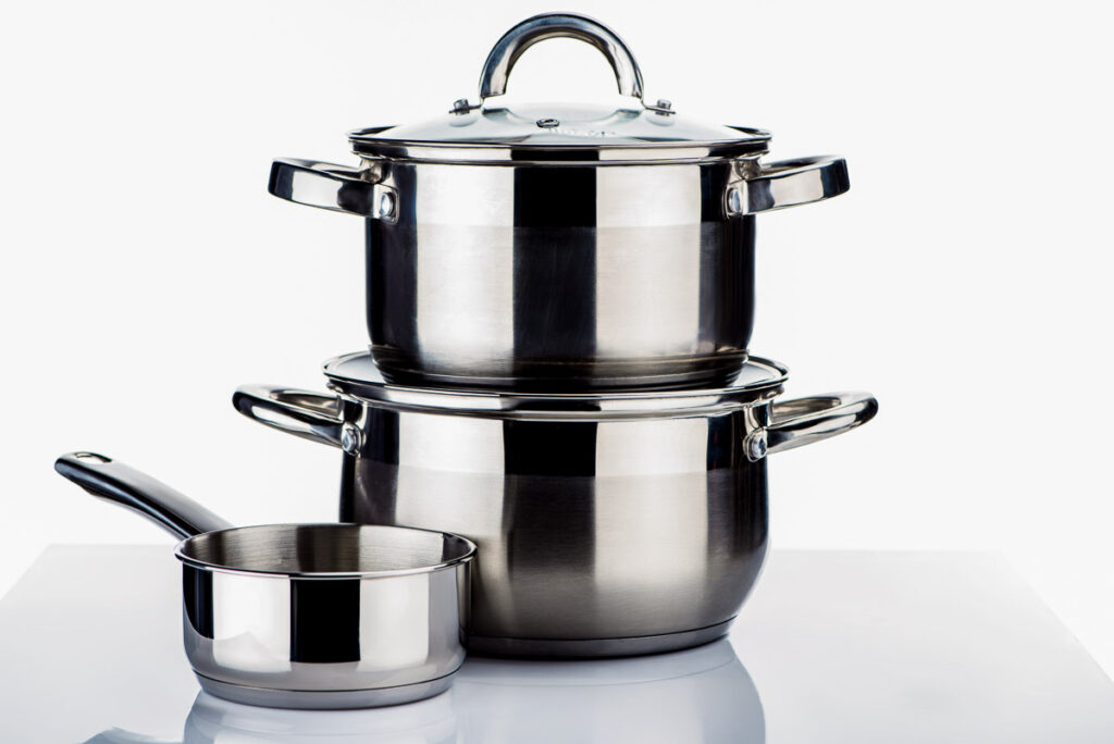 three stainless steel pots on a table, two in a stack and one to the side