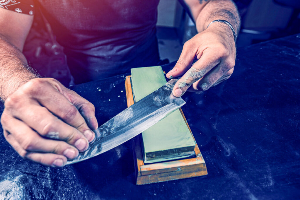 Knife sharpening. Close up of hand sharpening the chef knife