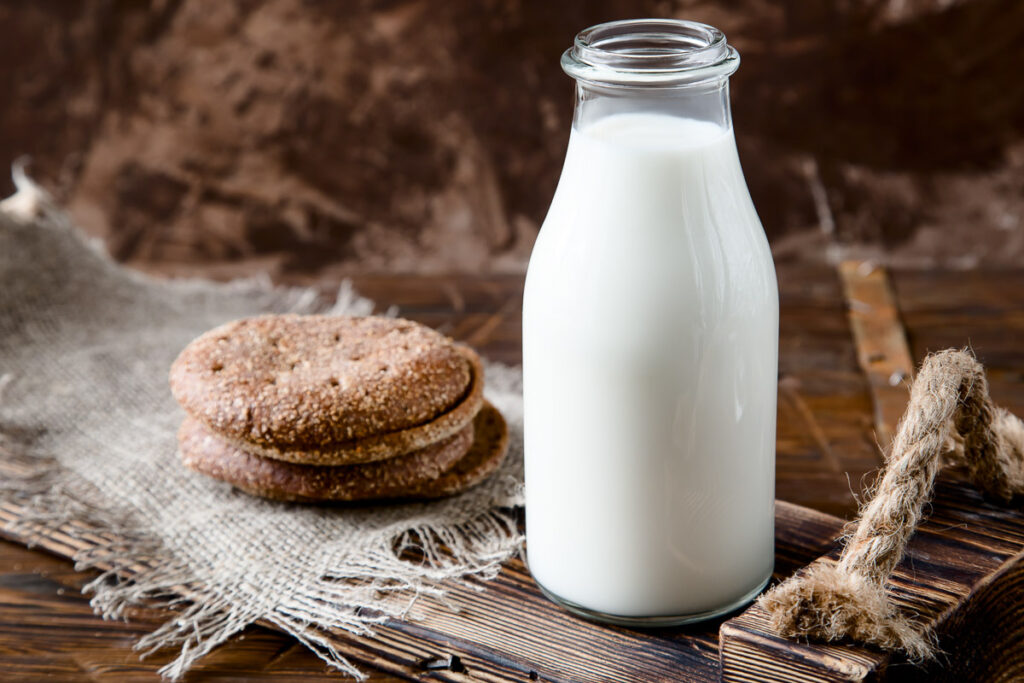 Natural whole milk in a bottle and on a old wooden background. horizontal