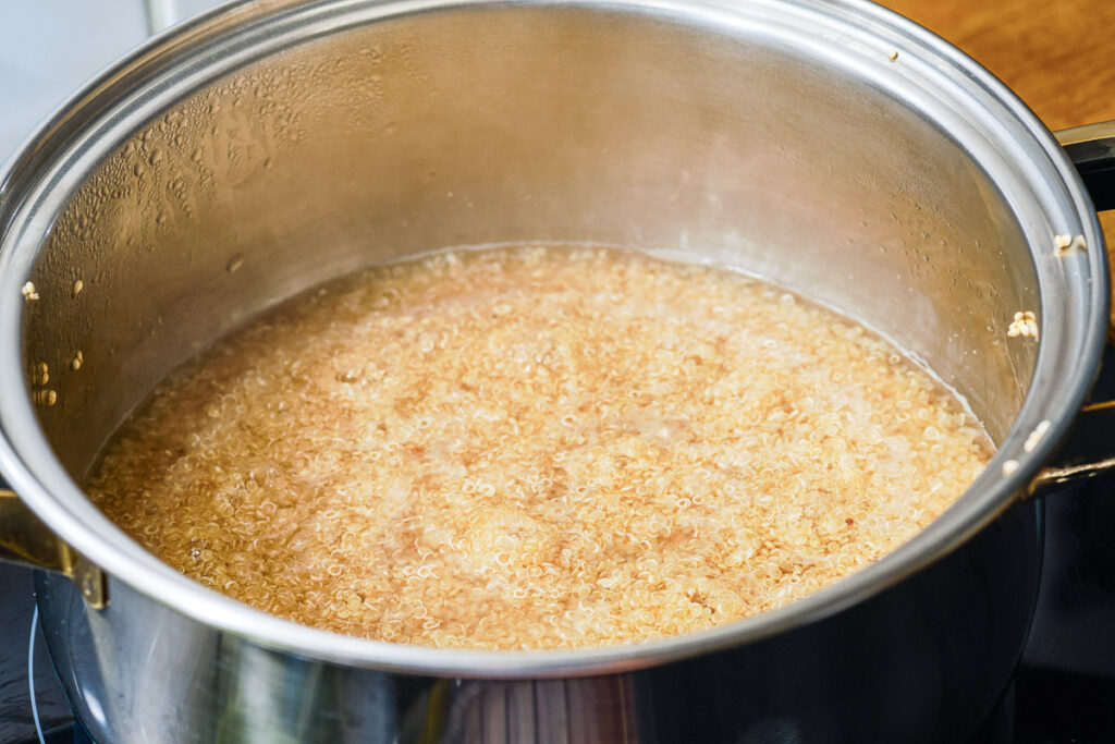 Preparing quinoa in boiling water in cooking pot on stove