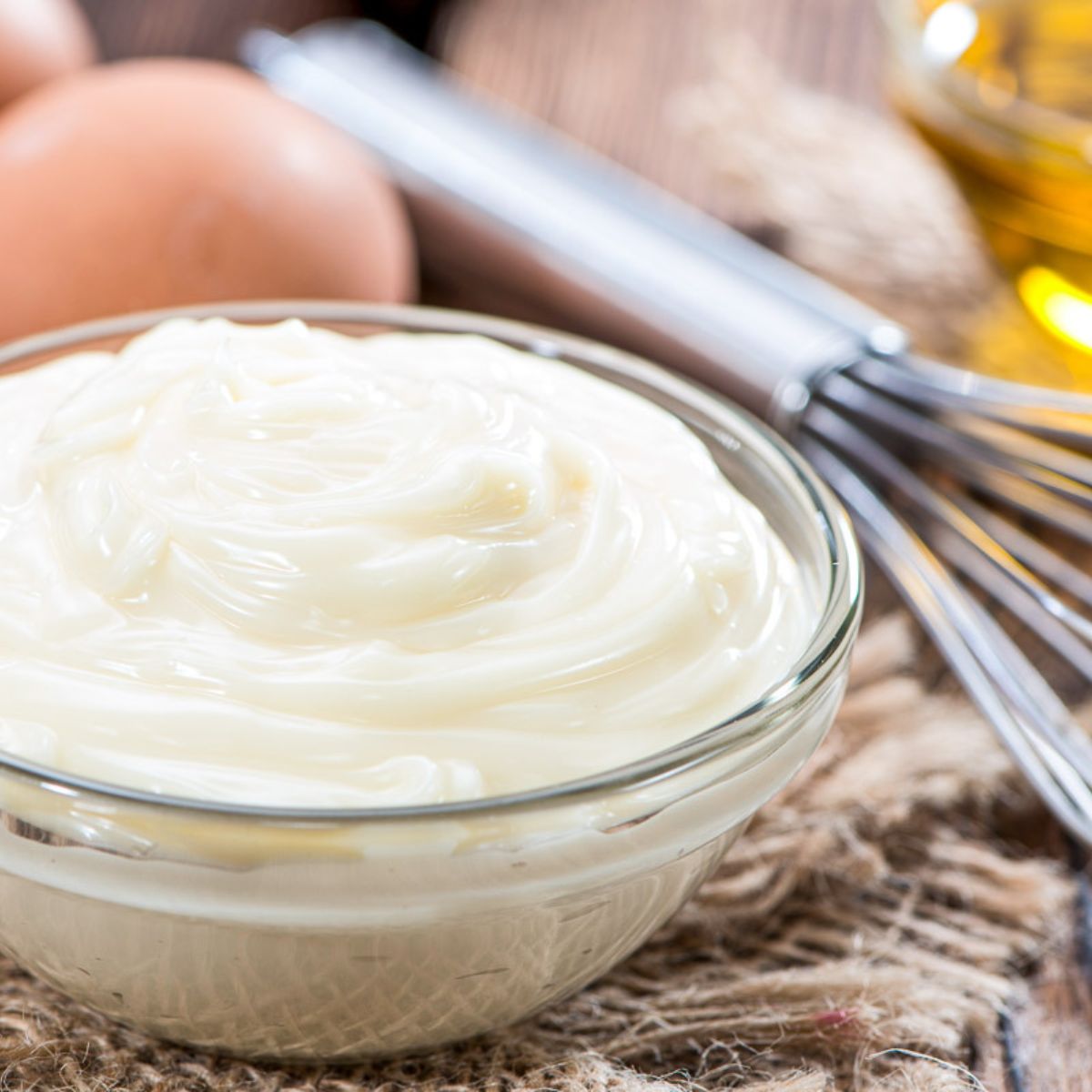 Fresh Mayonnaise (homemade) on an old wooden table with eggs, and oil - square
