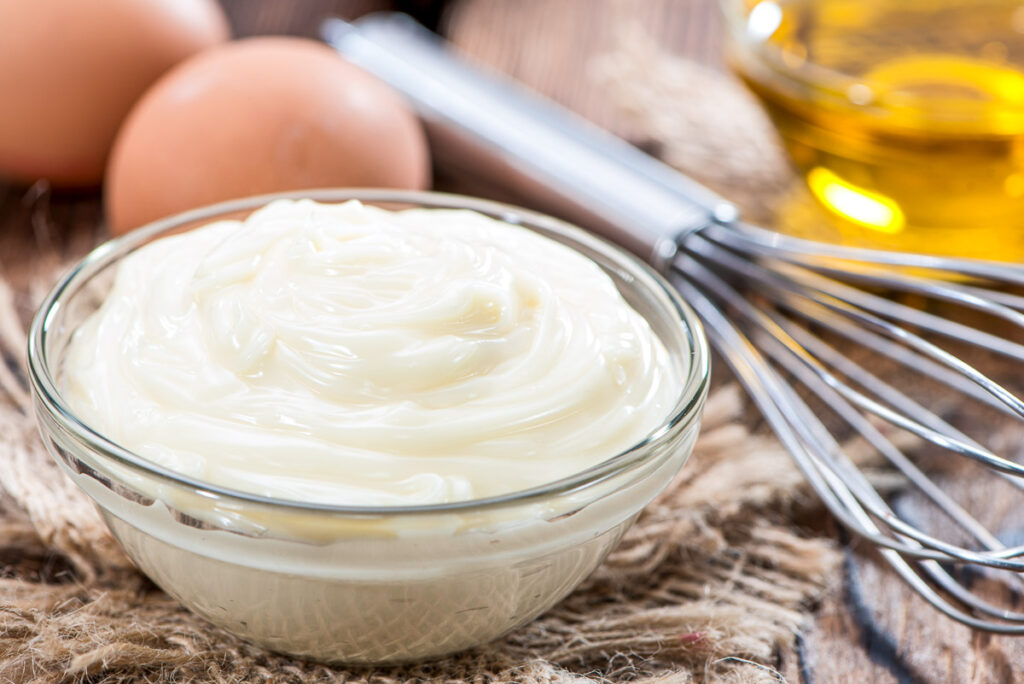 Fresh Mayonnaise (homemade) on an old wooden table with eggs, and oil